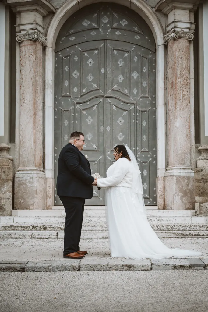 Romantisches Brautpaar-Porträt am Kloster Fürstenfeld Hochzeits-Paarshooting vor der barocken Kulisse von Kloster Fürstenfeld: Braut und Bräutigam halten Händchen und schauen sich verliebt an.