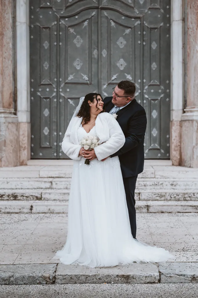 Innige Umarmung und tiefe Blicke Romantisches Hochzeitsfoto: Bräutigam umarmt die Braut von hinten und schaut ihr tief in die Augen beim Paarshooting am Kloster Fürstenfeld.