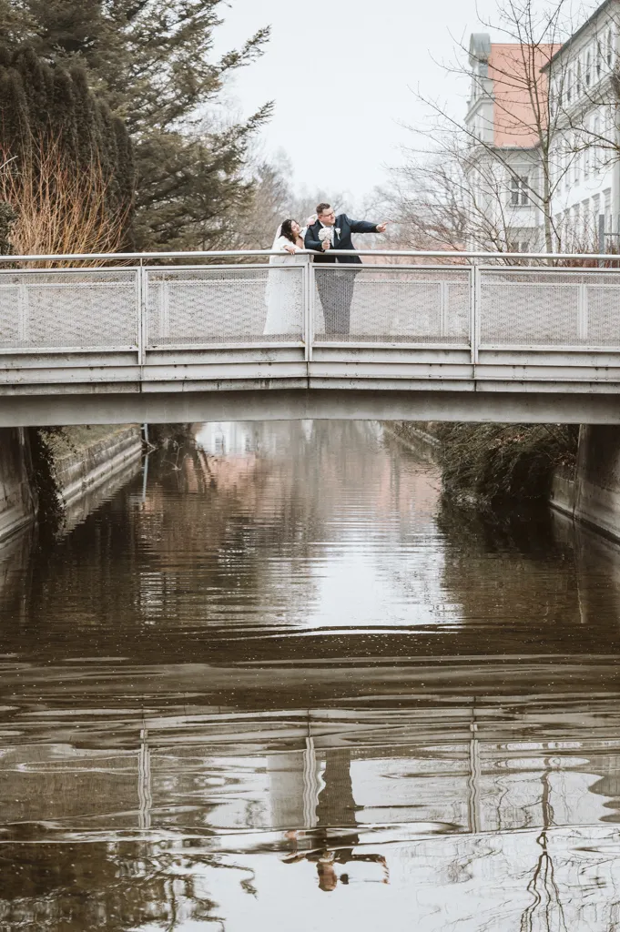 Entdeckungen am Amperufer Brautpaar steht auf einer Brücke in Fürstenfeldbruck; der Bräutigam zeigt der Braut etwas unten am Ufer der Amper.