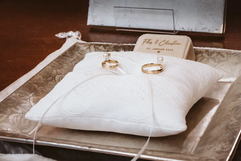 Eheringe auf dem Ringkissen Nahaufnahme der goldenen Eheringe auf einem eleganten weißen Ringkissen während der Trauzeremonie.