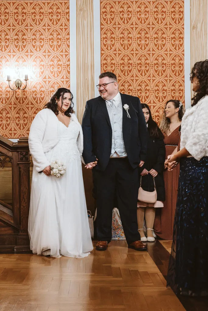 Der feierliche Einzug zur Trauung Einzug des Brautpaares in den festlich geschmückten Trausaal: Authentische Hochzeitsreportage während der standesamtlichen Trauung.