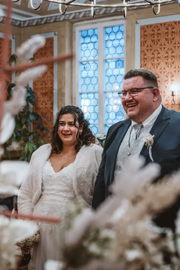 Glückstränen und Freudenstrahlen bei der Trauung Authentische Hochzeitsreportage: Braut weint vor Freude während der Trauung, daneben der lächelnde Bräutigam in einem emotionalen Moment.