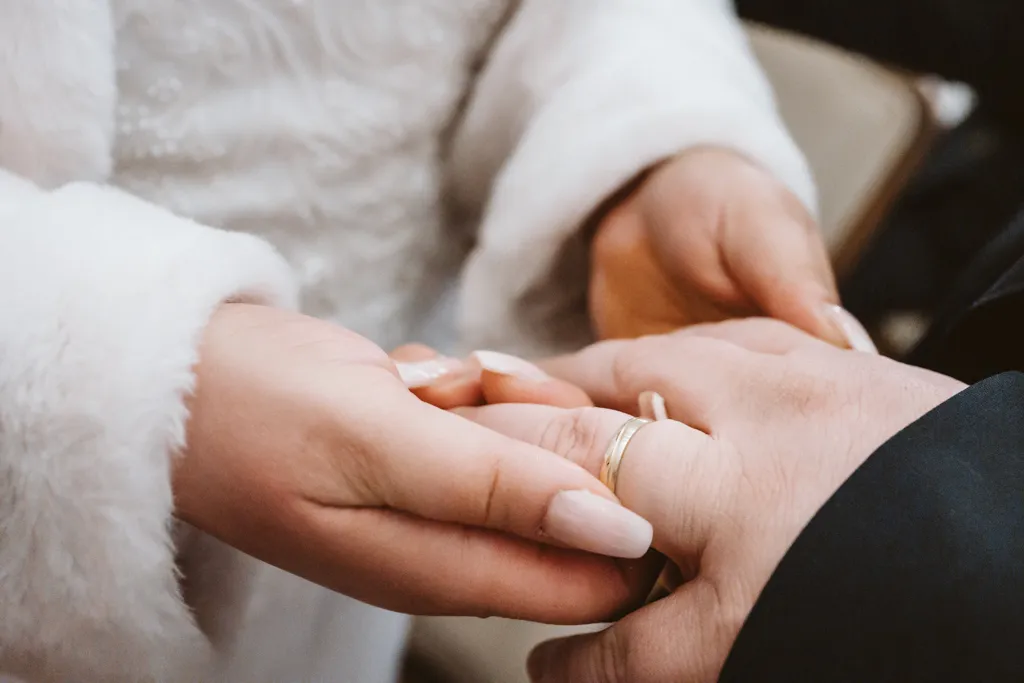 Emotionaler Ringtausch bei der Hochzeit Der Moment des Ringtauschs: Brautpaar steckt sich gegenseitig die Eheringe während der Trauzeremonie an.