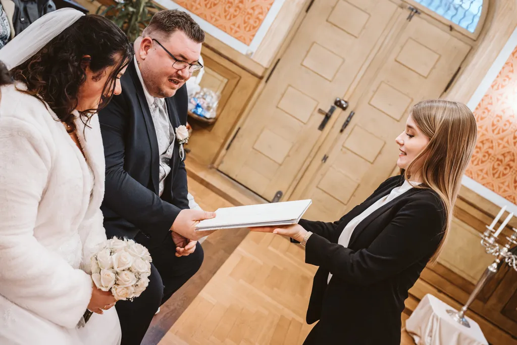 Die offizielle Übergabe der Hochzeitsurkunde Überreichung der Heiratsurkunde durch die Standesbeamtin an das frisch vermählte Ehepaar im Standesamt.