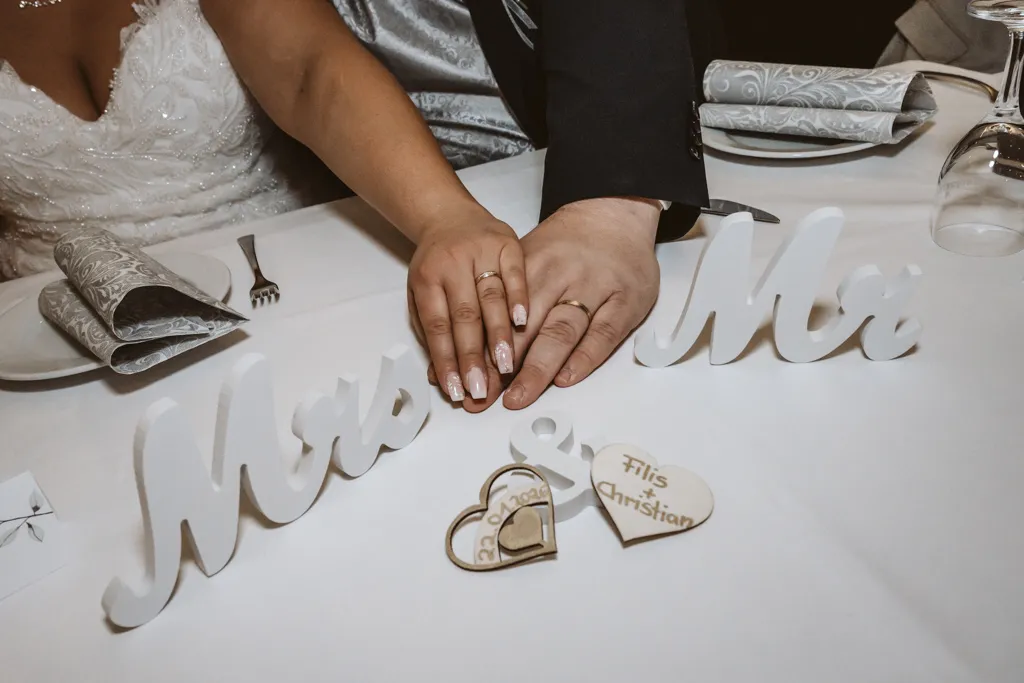 Die Eheringe als Symbol der Verbundenheit Nahaufnahme der Hände von Braut und Bräutigam, die übereinander liegen und die glänzenden Eheringe zeigen.