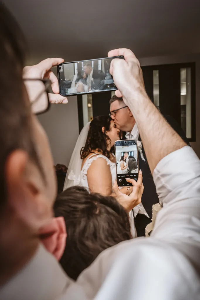 Der „Paparazzi-Moment“ der Gäste Begeisterte Hochzeitsgäste fotografieren das Brautpaar mit ihren Smartphones während der Feier. Ein authentischer Moment der Reportage.