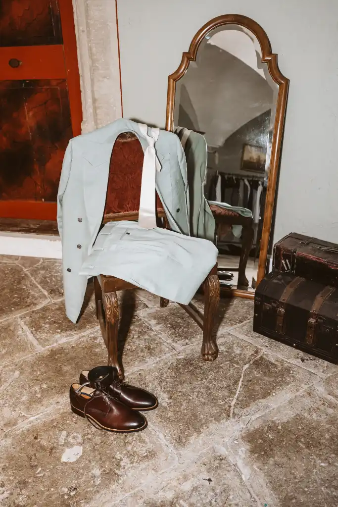 Bräutigamkleidung auf einem Stuhl im Schlossraum Hochzeitsanzug und Kleidung des Bräutigams liegen auf einem Stuhl im Schlossraum