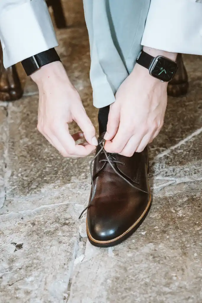Getting Ready – Bräutigam zieht seine Schuhe an Bräutigam bindet sich beim Getting Ready die Hochzeitschuhe zu
