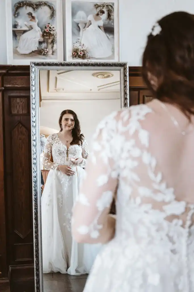 Getting Ready – Braut sieht sich im Spiegel an Braut blickt beim Getting Ready strahlend in den Spiegel
