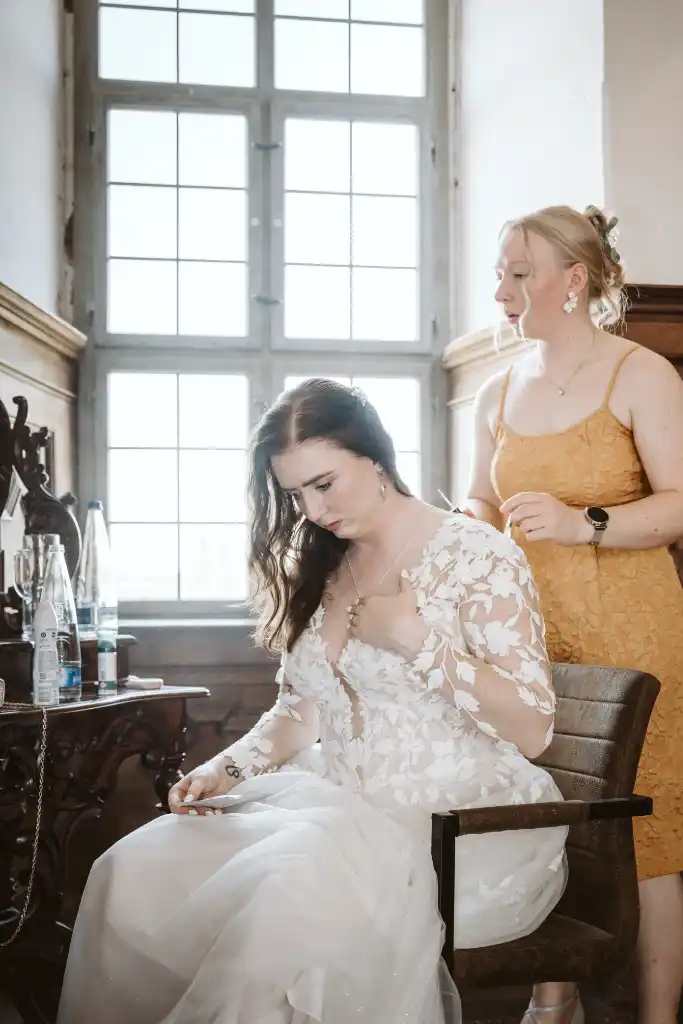 Getting Ready – Braut sitzt im Schlossraum Braut sitzt im Brautkleid während des Getting Ready im Schlossraum auf einem Stuhl