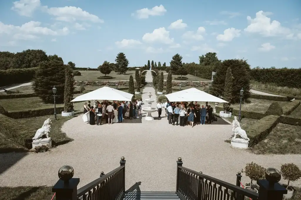 Hochzeitsgesellschaft – Versammelte Gäste vor dem Schloss Die versammelte Hochzeitsgesellschaft wartet gespannt und gut gelaunt vor dem imposanten Schloss