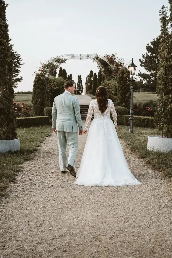 Brautpaar-Shooting – Gefühlvoller Spaziergang im Garten Das glückliche Brautpaar blickt sich verliebt an beim romantischen Spaziergang durch den Garten