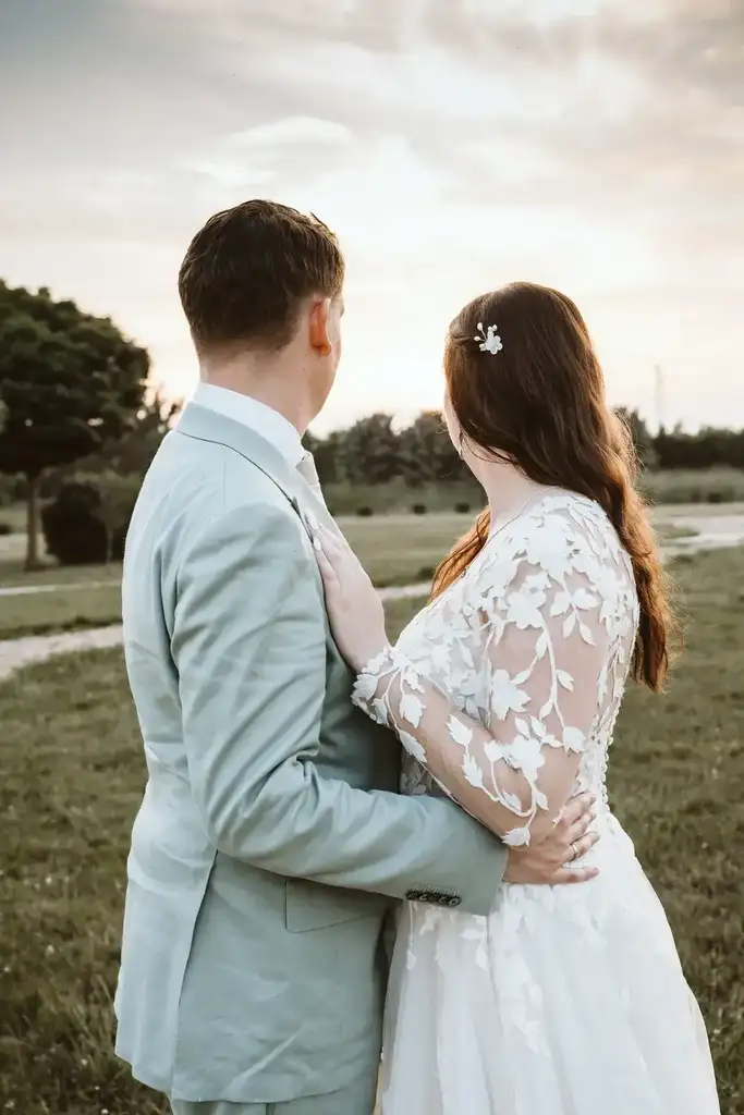 Brautpaar-Shooting – Gemeinsamer Blick in den Sonnenuntergang Das Brautpaar blickt gemeinsam Hand in Hand in den farbenprächtigen Abendhimmel des Sonnenuntergangs