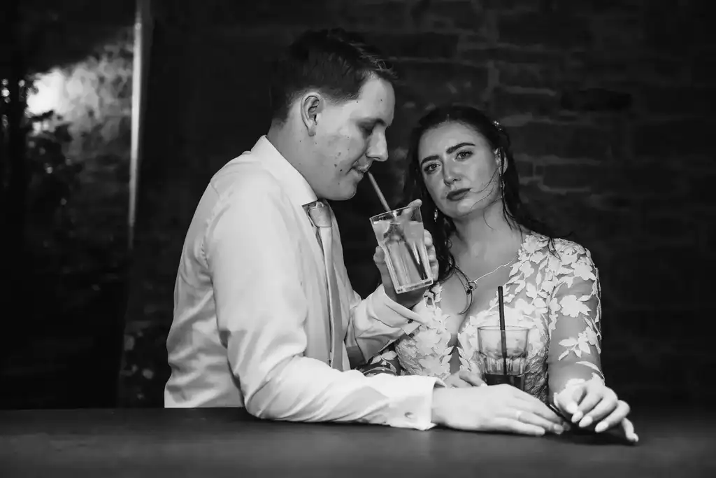 Brautpaar-Shooting – Romantische Schwarz-Weiß-Szene an der Bar Elegante Schwarz-Weiß-Aufnahme: Das Brautpaar lehnt entspannt an der Bar und teilt einen vertrauten, intimen Moment