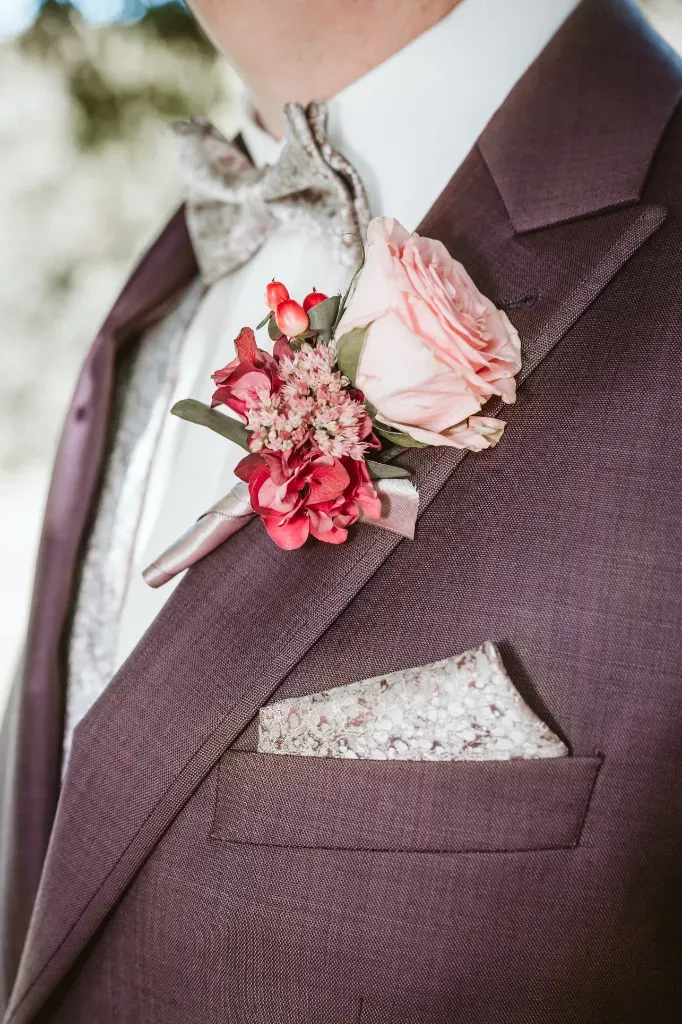Detail: Rose am Jacket des Bräutigams Detailaufnahme der eleganten Anstecknadel (Boutonnière) – einer einzelnen Rose – am Revers des Jackets des Bräutigams