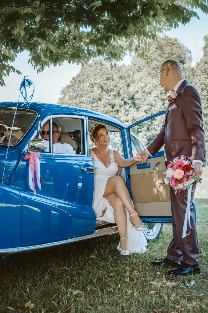 Die Braut steigt aus dem blauen Oldtimer Hochzeitsbilder aus Olching: Die Braut steigt elegant aus dem blauen Oldtimer (Hochzeitsfahrzeug) aus