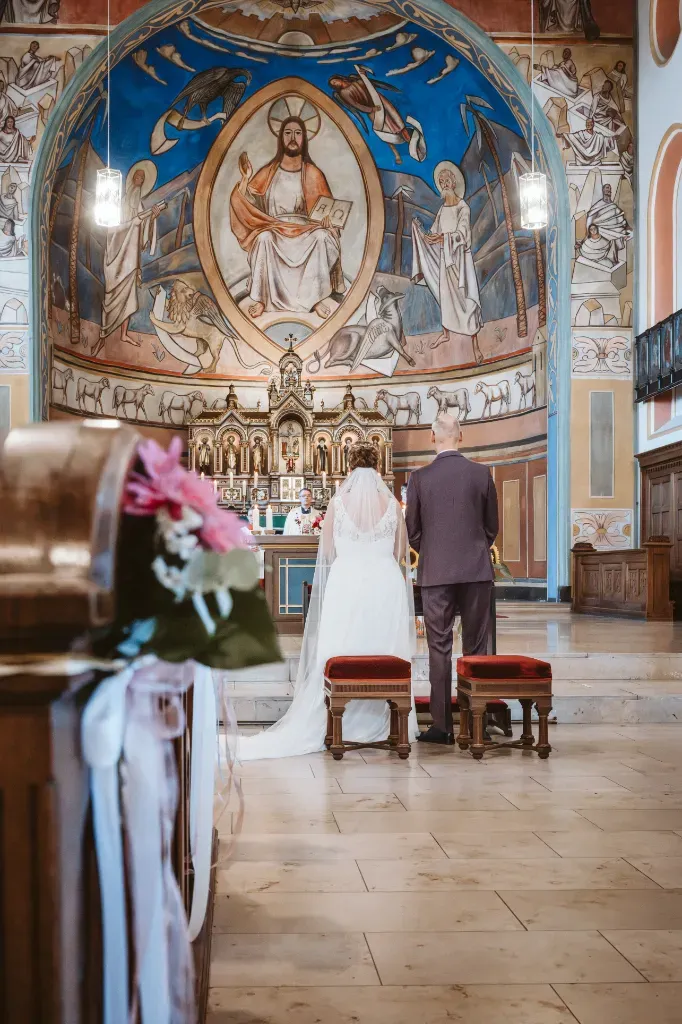 Brautpaar vor dem Altar in der Kirche Olching Das Brautpaar steht bei der Trauung in der Kirche in Olching vor dem Altar, während der Priester im Hintergrund die Zeremonie leitet.