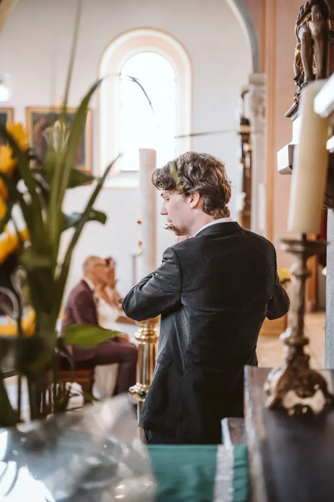 Musiker mit Querflöte in der Kirche Fotograf Olching: Detailaufnahme der musikalischen Untermalung der Trauung in Olching, bei der Musiker mit einer Querflöte die Zeremonie begleiten