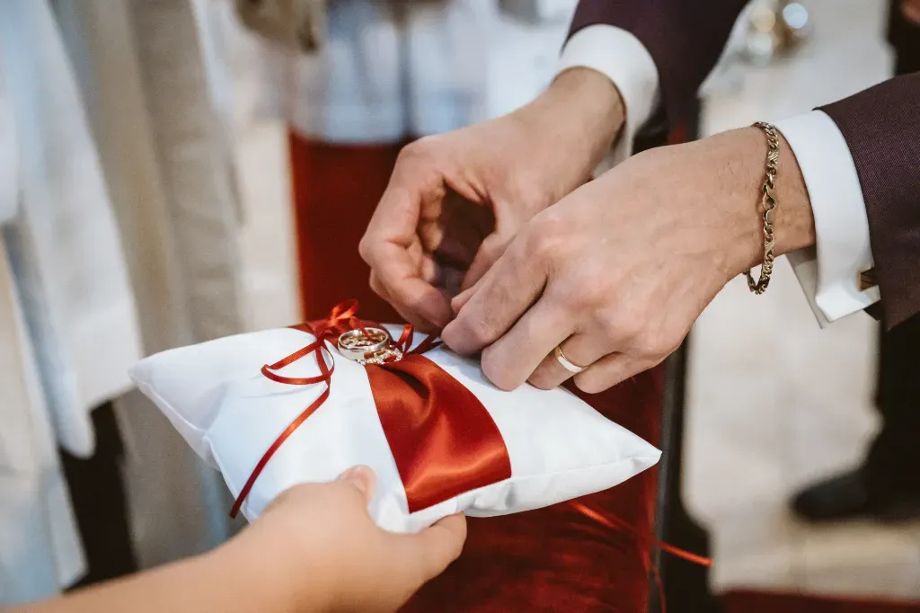 Ringtausch: Eheringe werden vom Kissen genommen Nahaufnahme der Eheringe, die kurz vor dem Ringtausch vom Kissen genommen werden. Dieser Moment markiert den Beginn des feierlichen Teils der Zeremonie in Olching.