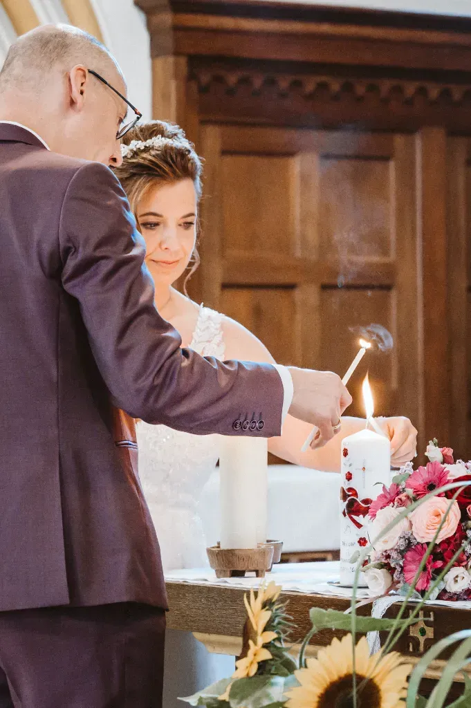 Brautpaar entzündet die Hochzeitskerze ochzeitsfotografie Olching: Symbolischer Moment, in dem das Brautpaar gemeinsam die Hochzeitskerze anzündet. Dieser Brauch symbolisiert die Einheit und den gemeinsamen Weg des Paares.