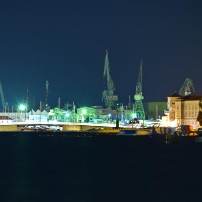 Nachtaufnahme in Langzeit. Die Stad wird von Gelben, Grünen und Blauen Lampen beleuchtet.