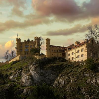 Das gelbe Schloss Hohenschwangau vereint sich mit dem goldbraune Himmel.