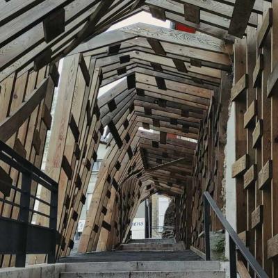 Eine ungleichmäßige Holzkonstruktion überdacht einen Gehweg