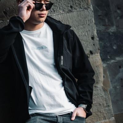 Junger asiatischer Mann lehnt an einer Wand und schaut über seine Brille